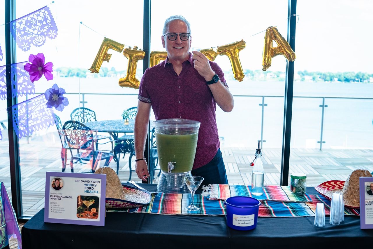 A Doctender pouring a drink at their table under the FIESTA balloons